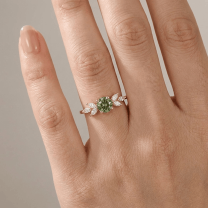 Anel delicado de ouro com peridoto verde em formato de folha, da marca Rose & Oliver, exibido em fundo neutro.