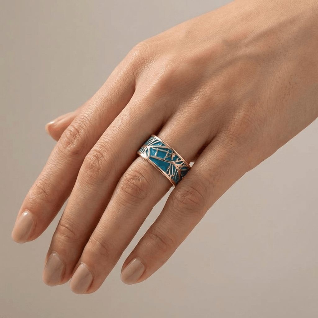 Anillo de oro rosé con piedra turquesa y diseño místico, de la marca Rose & Oliver, mostrado en primer plano en la imagen.