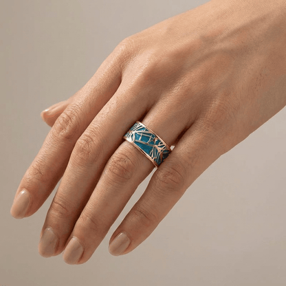 Anillo de oro rosé con piedra turquesa y diseño místico, de la marca Rose & Oliver, mostrado en primer plano en la imagen.