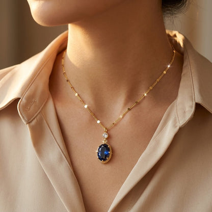 Colar dourado com pingente de safira oval, acabamento elegante, da marca Rose & Oliver, exibido em fundo neutro.