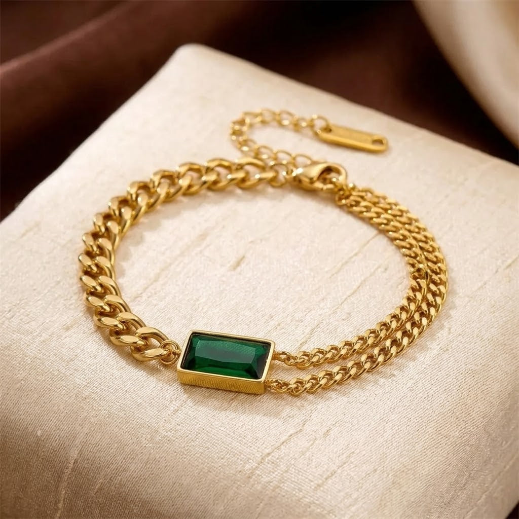 Pulseira de ouro e esmeralda Rose & Oliver, com corrente de barra e detalhes elegantes, visível na imagem.
