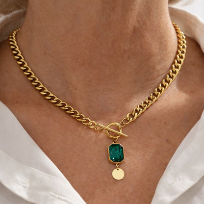 Collar con colgante de esmeralda de Rose & Oliver, destacado en la imagen, con cadena de plata y piedra verde brillante.