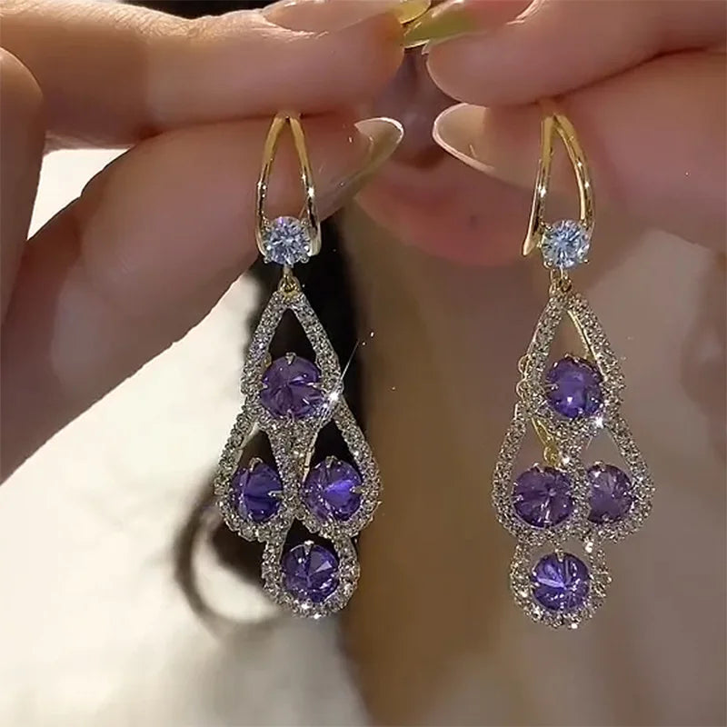 Aretes de gota con cristal morado de Rose & Oliver, elegantes y brillantes, colgados en alambre de metal plateado.