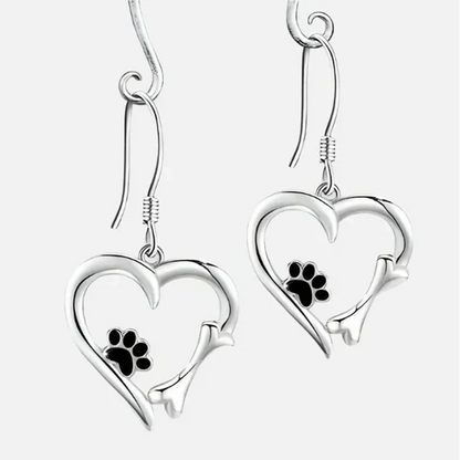 Aretes Yaritza™ de Rose & Oliver con colgantes de pata y corazón en plata, estilo delicado y elegante, visibles en la imagen.