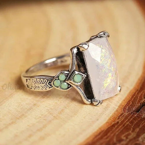Anillo vintage de plata con ópalo blanco, diseño elegante de la marca Rose & Oliver, exhibido sobre fondo neutro.