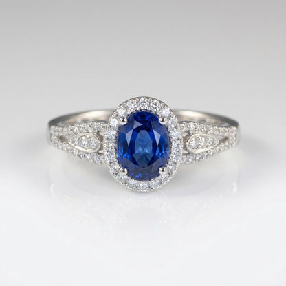 Vintage-Ring Rose & Oliver mit blauem Saphir-Halo und Silberdetails, Hervorhebung für das elegante Design und den strahlenden zentralen Stein.