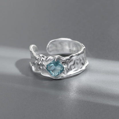 Anel ajustável Rose & Oliver com textura prateada e pedra de aquamarina brilhante, exibido em close.