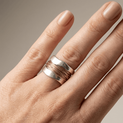 Anillo artesanal de plata y oro con encuadernación de hilo, de la marca Rose & Oliver, mostrado en detalle en la imagen.