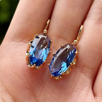 Brincos dourados e azuis com design floral da marca Rose & Oliver, detalhes delicados e acabamento elegante.